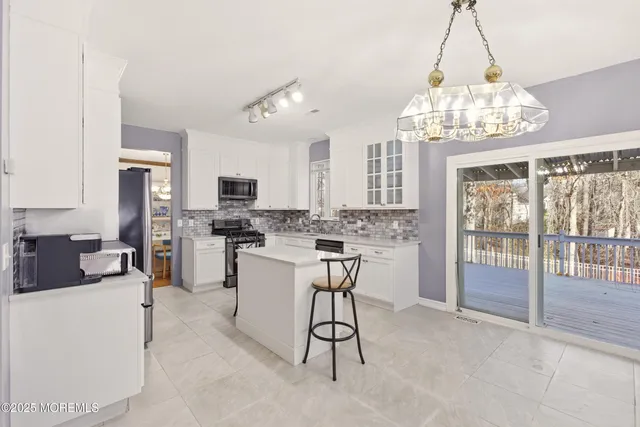 a view of a dining room with furniture a chandelier and kitchen view