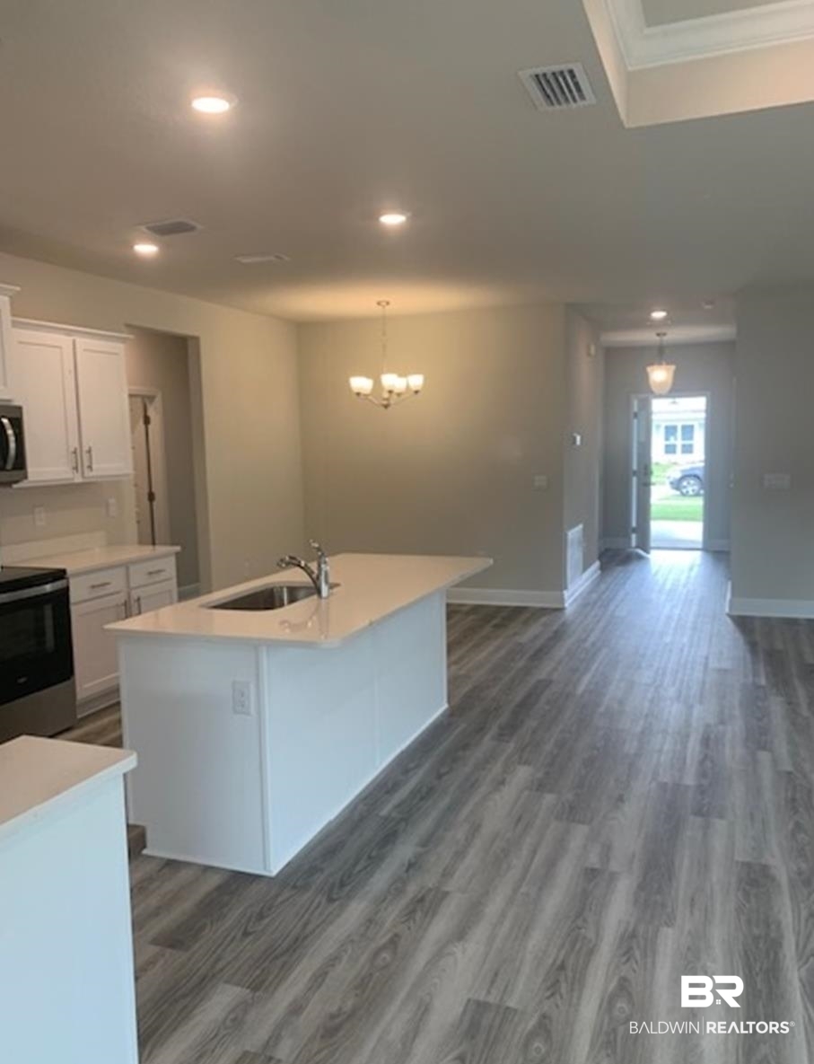 12904 Grand Rpds Road Fairhope, AL 36532 - Photo 21 of 34 Kitchen featuring a center island with sink, white cabinets, sink, dark hardwood / wood-style floors, and appliances with stainless steel finishes
