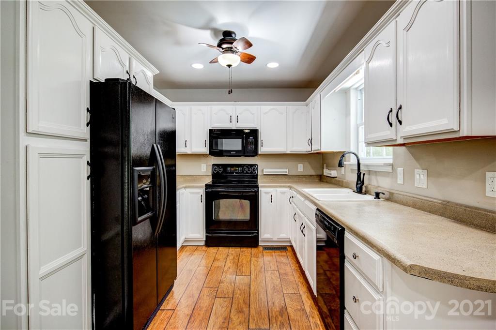 4004 Belk Mill Road Wingate, NC 28174 - Photo 13 of 44 a kitchen with a sink a refrigerator a microwave and cabinets