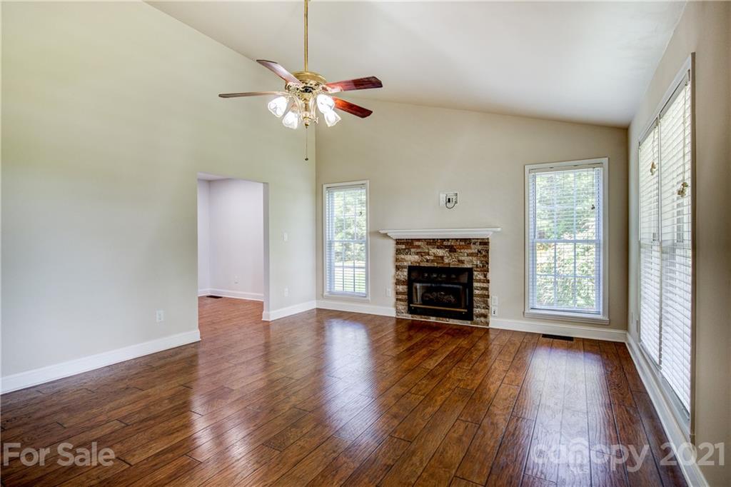 4004 Belk Mill Road Wingate, NC 28174 - Photo 7 of 44 an empty room with wooden floor fireplace and large window