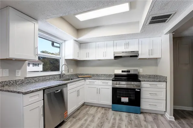 a kitchen with stainless steel appliances granite countertop a stove sink and cabinets