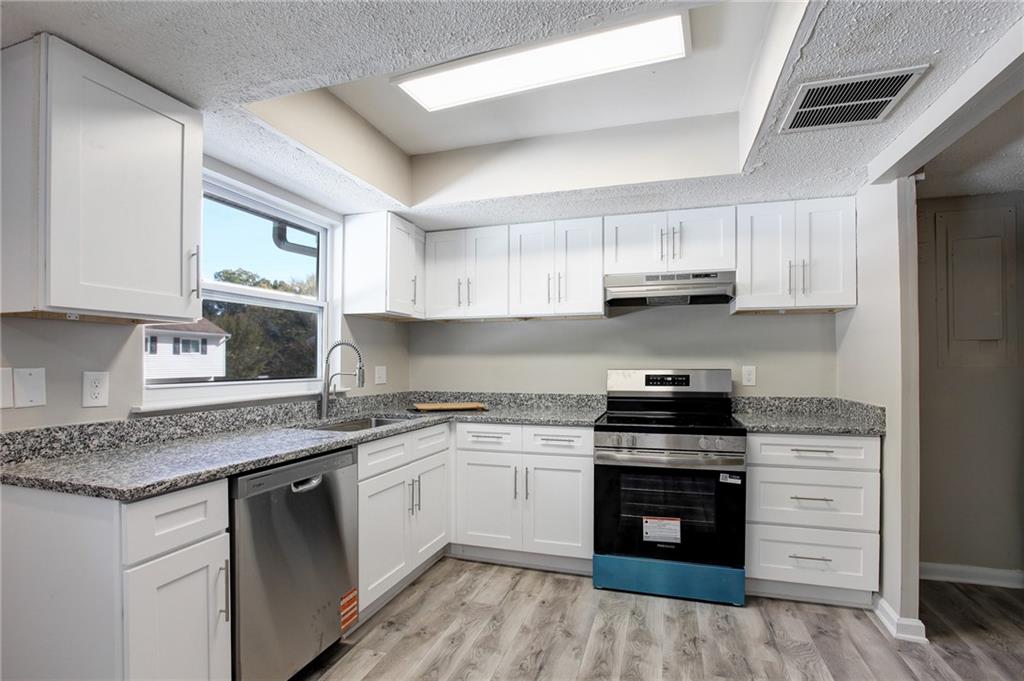 a kitchen with stainless steel appliances granite countertop a stove sink and cabinets