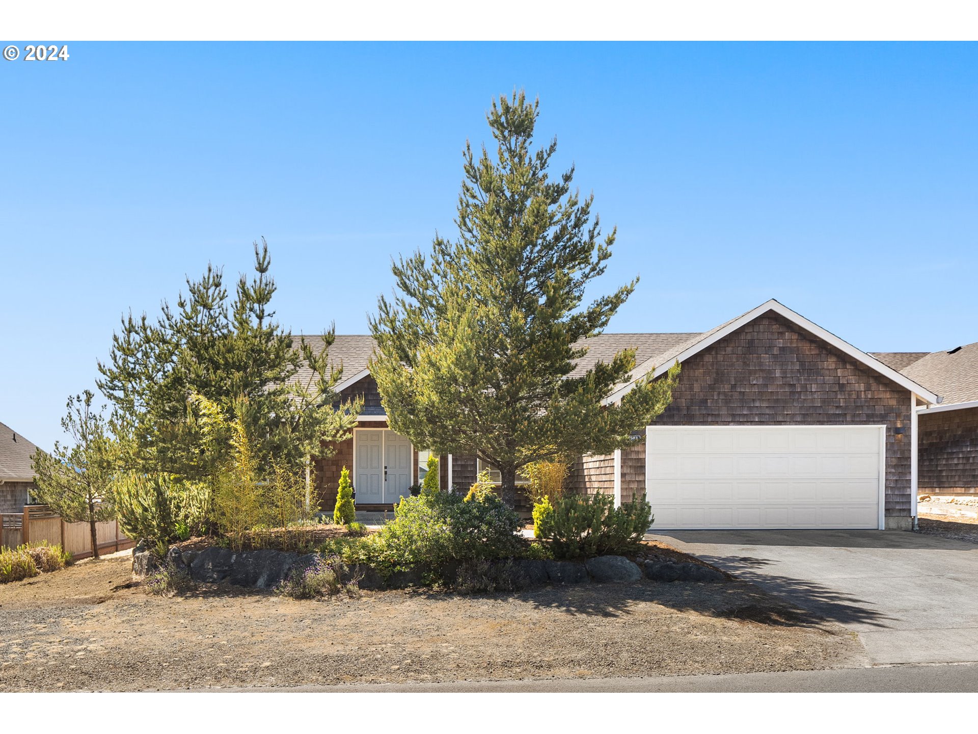 9980 Pine Ridge Drive Nehalem, OR 97131 - Photo 1 of 27 a front view of a house with a yard and garage