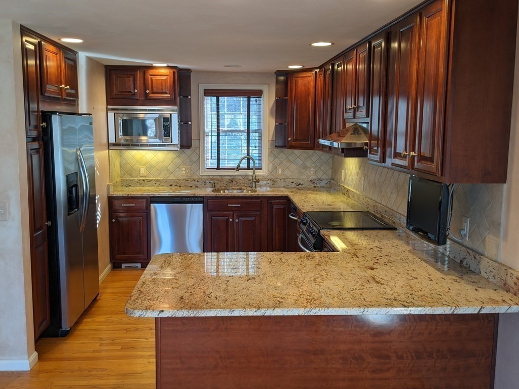 44 Boxford Road, Unit 44 Haverhill, MA 01835 - Photo 4 of 13 a kitchen with kitchen island granite countertop wooden cabinets a oven and granite counter tops
