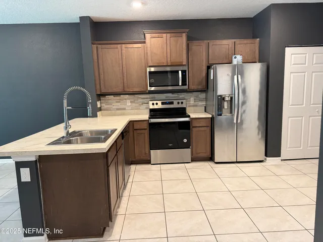 a kitchen with stainless steel appliances a sink a stove a microwave a counter top space and cabinets