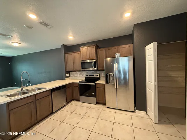 a kitchen with stainless steel appliances granite countertop a refrigerator and a sink