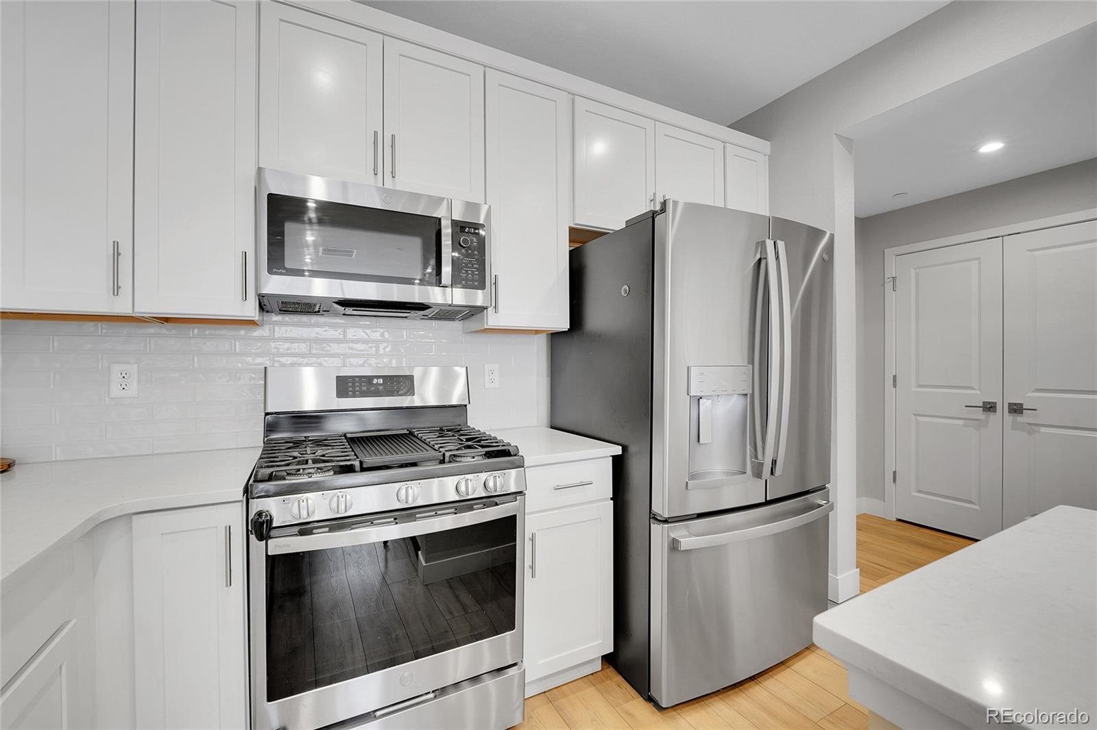 6211 West 28th Avenue Wheat Ridge, CO 80214 - Photo 16 of 29 a kitchen with stainless steel appliances white cabinets white stove a microwave and a refrigerator