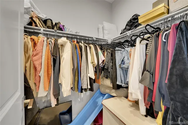 a view of walk in closet with clothes and shoes