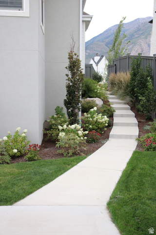7 Elk Court Alpine, UT 84004 - Photo 10 of 10 Concrete pathway leading to stepped walkway, bordered by verdant landscaping with flowering shrubs, mature trees, and natural stone elements