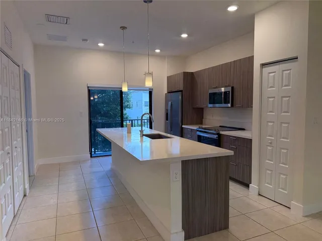 a large kitchen with kitchen island granite countertop a sink and a refrigerator