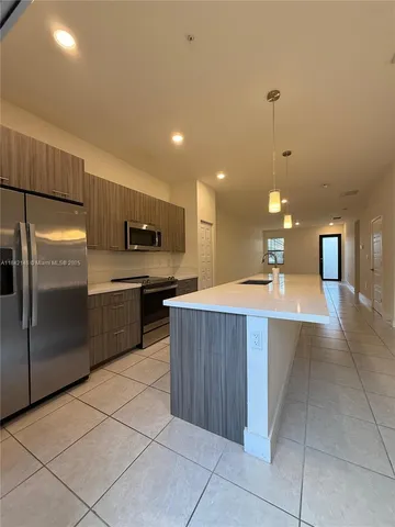 a large kitchen with a large counter top stainless steel appliances and cabinets