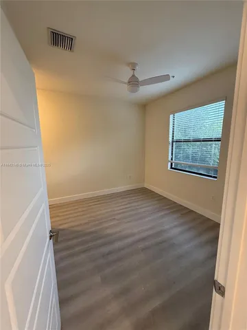 a view of a room with wooden floor and a ceiling fan
