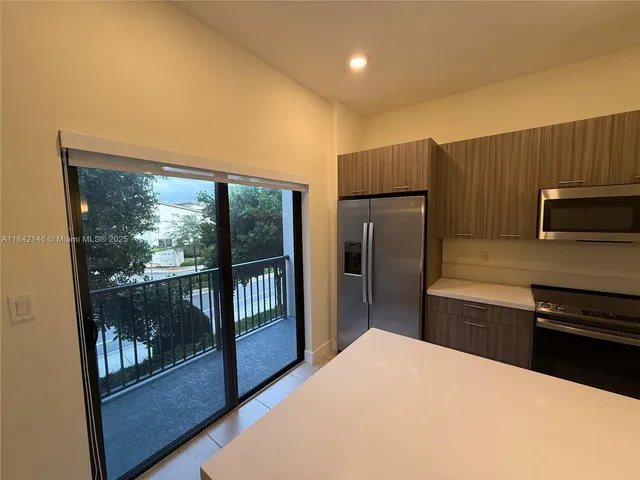 a kitchen with granite countertop a refrigerator and a stove top oven