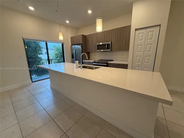 a large kitchen with stainless steel appliances a large counter top a stove a refrigerator a sink and dishwasher