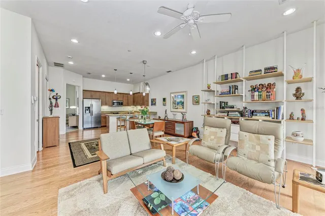 a living room with furniture kitchen view and a wooden floor