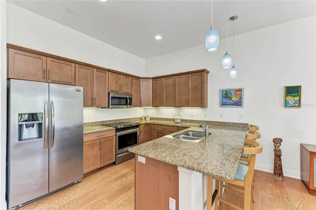 a kitchen with stainless steel appliances granite countertop a kitchen island hardwood floor sink and stove