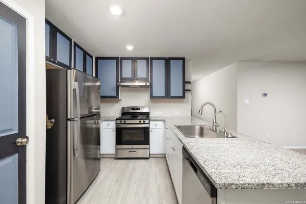 a kitchen with granite countertop kitchen island stainless steel appliances a refrigerator stove top oven and sink