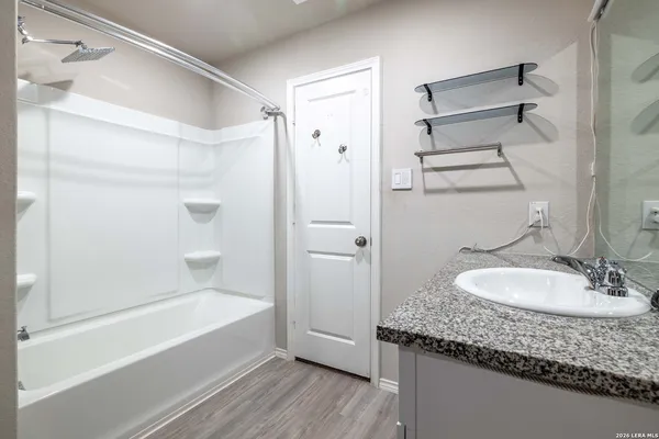 a bathroom with a granite countertop tub sink and mirror