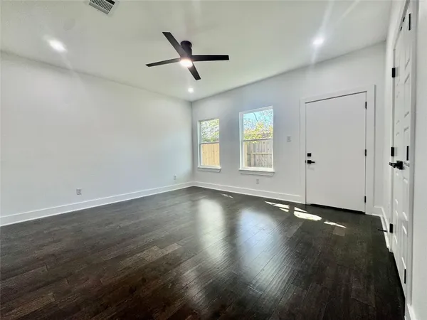 an empty room with wooden floor and windows