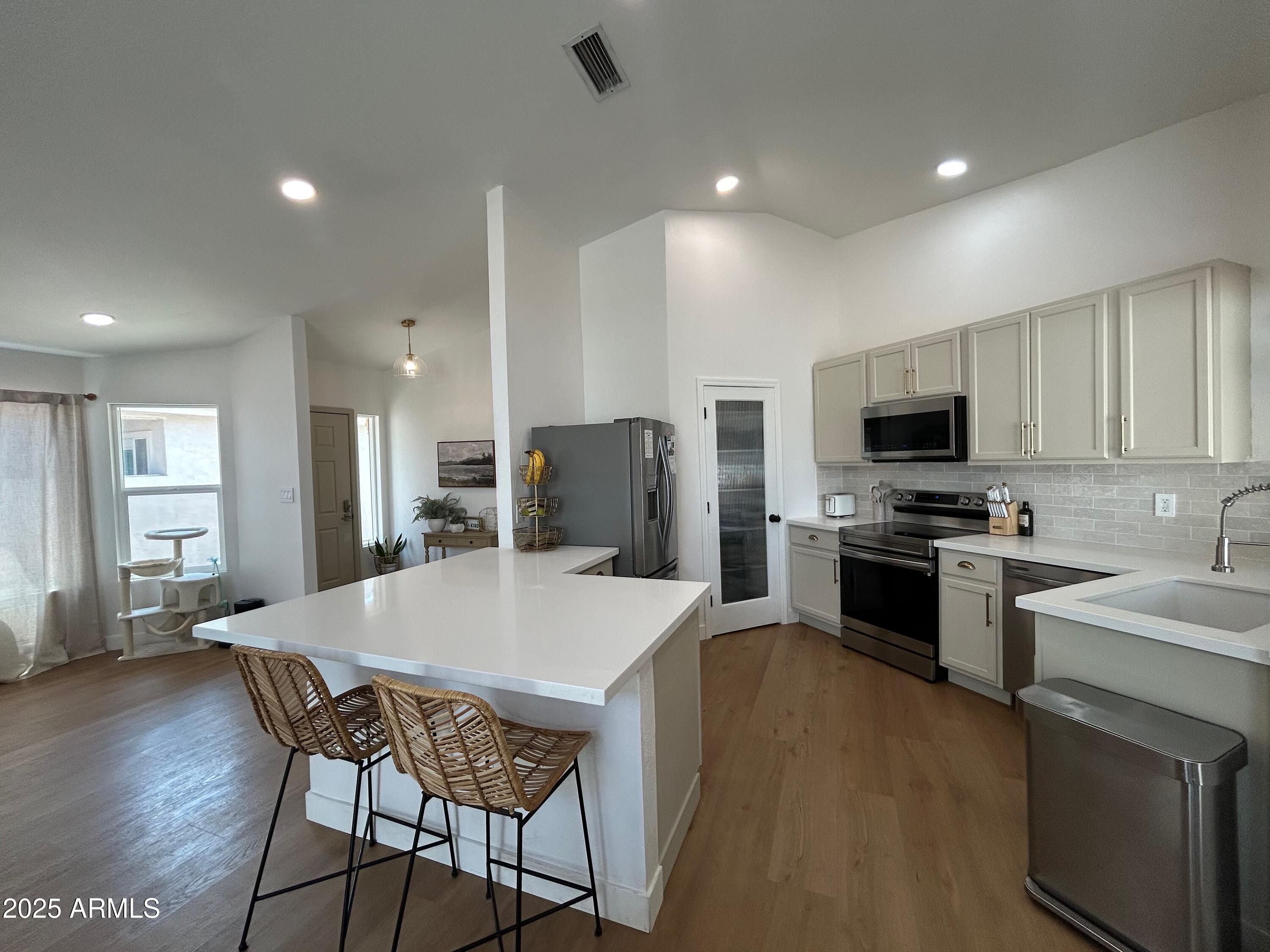 4725 East Brown Road, Unit 57 Mesa, AZ 85205 - Photo 4 of 14 a kitchen with stainless steel appliances a stove a sink a microwave a refrigerator white cabinets a dining table and chairs