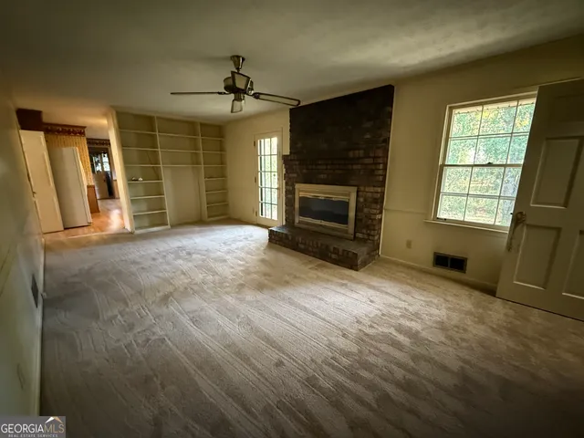an empty room with windows fireplace and wooden floor