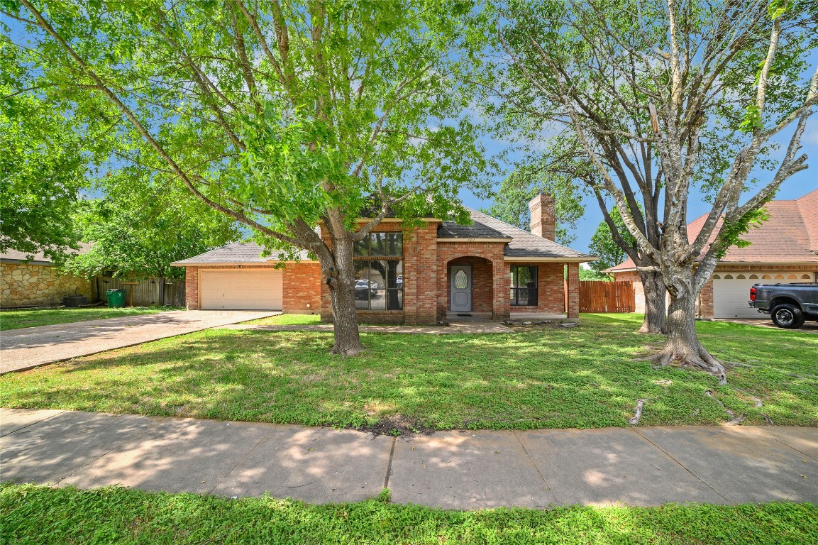 a front view of a house with a garden and trees