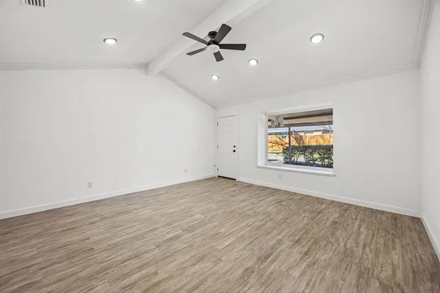 an empty room with wooden floor and ceiling fan