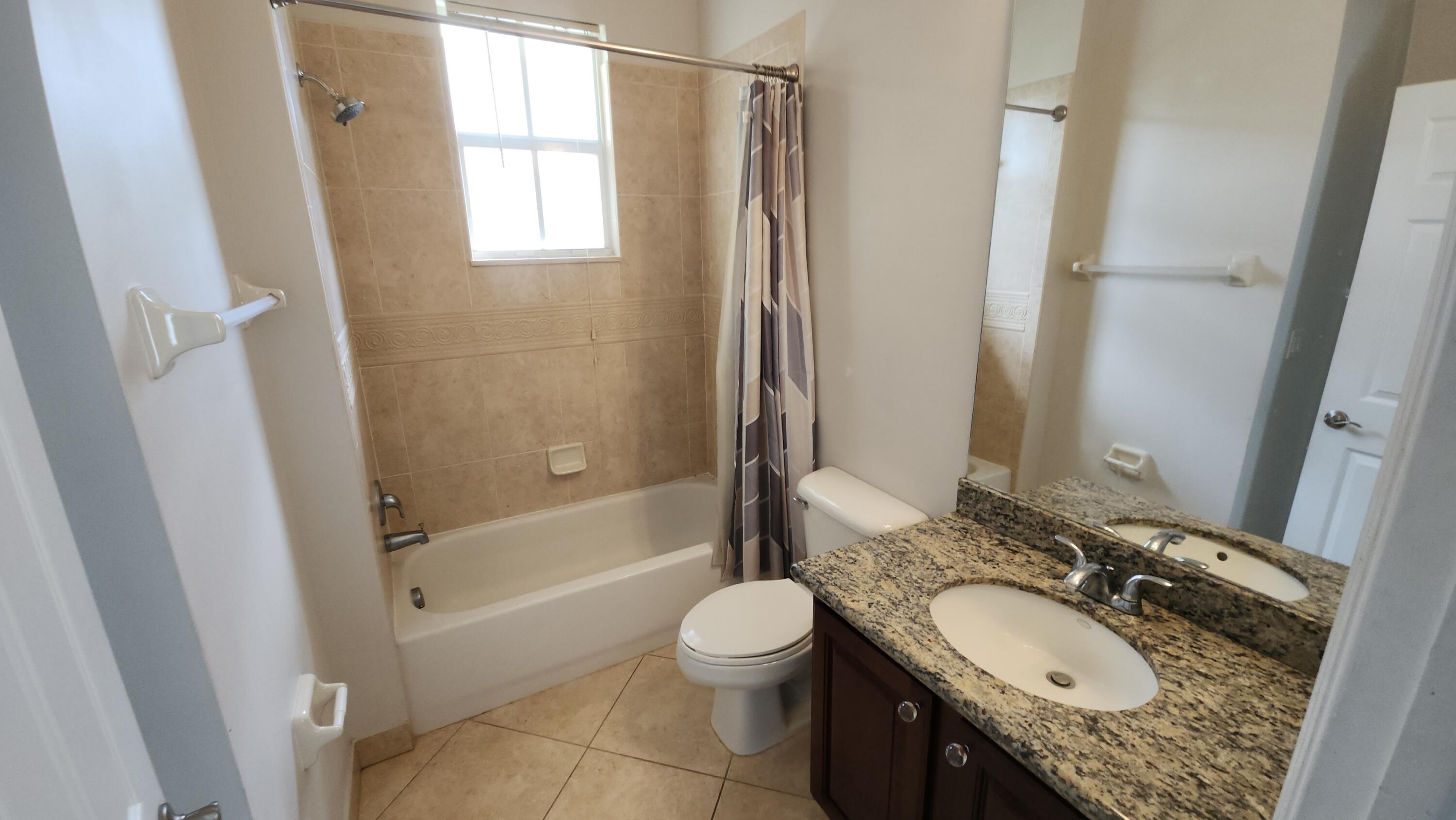 909 Northwest 18th Avenue Boca Raton, FL 33431 - Photo 25 of 39 a bathroom with a granite countertop sink toilet mirror and shower