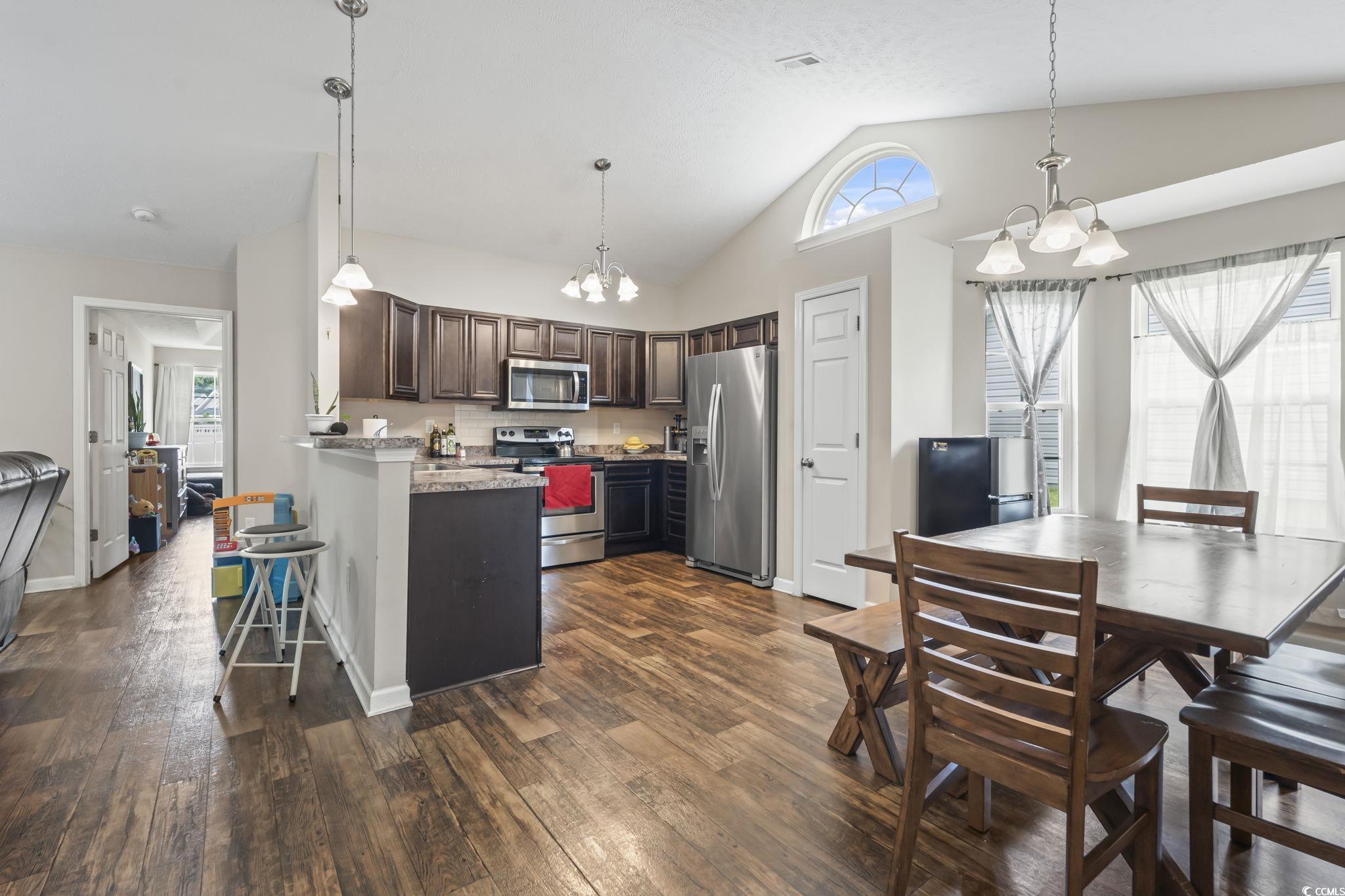 282 Foxpath Loop Myrtle Beach, SC 29588 - Photo 11 of 34 Kitchen with appliances with stainless steel finishes, a chandelier, dark brown cabinetry, a peninsula, and dark wood-style floors