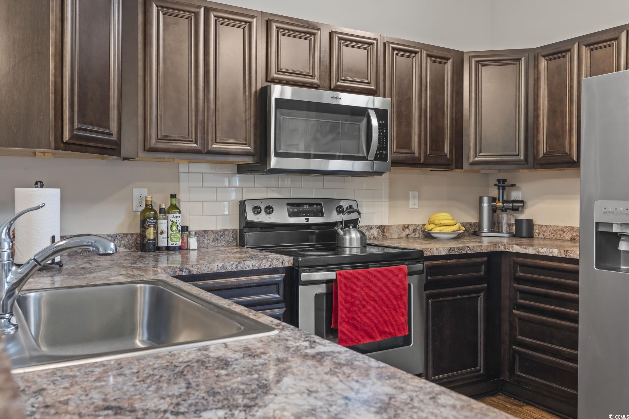 282 Foxpath Loop Myrtle Beach, SC 29588 - Photo 3 of 34 Kitchen featuring stainless steel appliances, a sink, dark brown cabinets, and backsplash