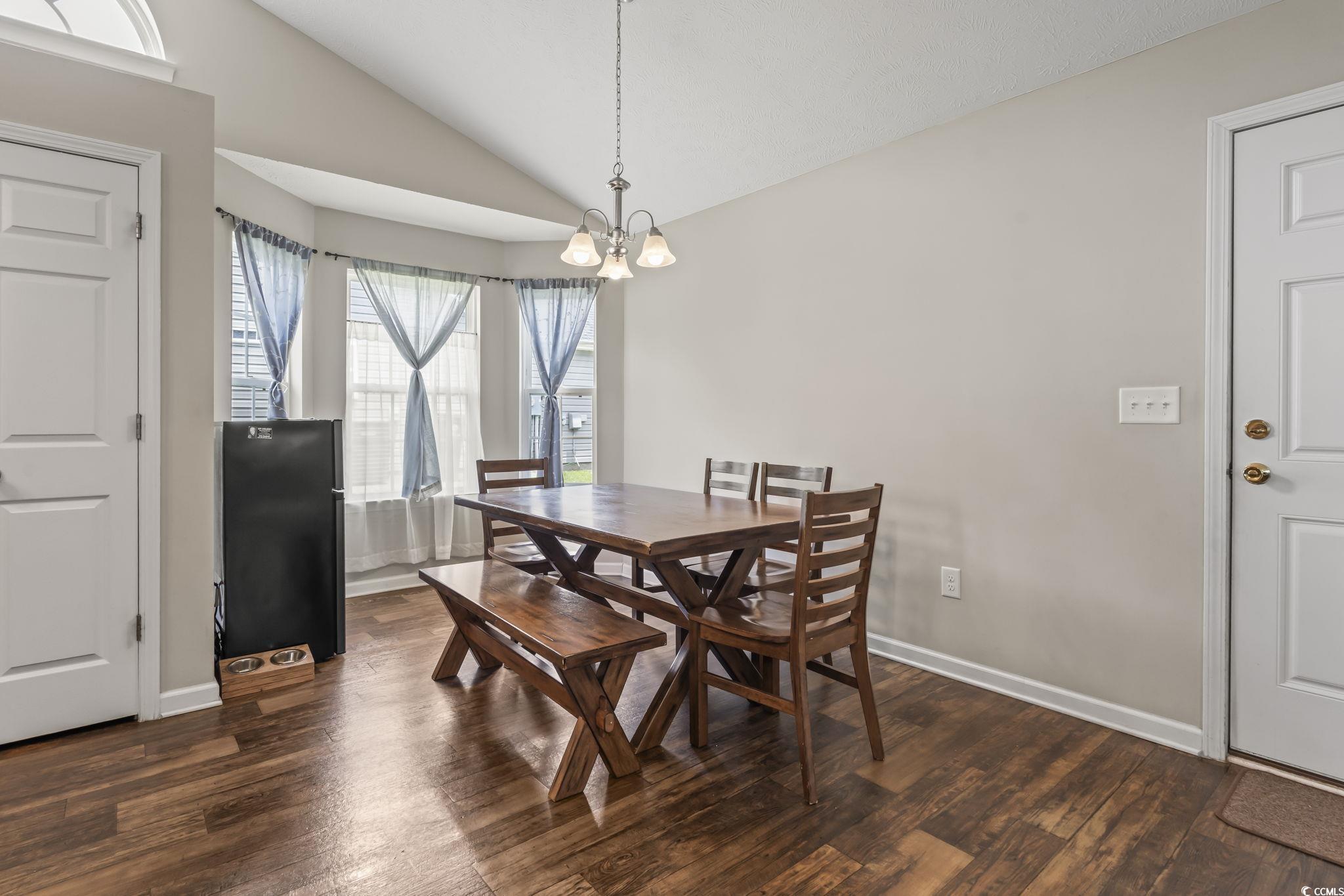 282 Foxpath Loop Myrtle Beach, SC 29588 - Photo 10 of 34 Dining space featuring lofted ceiling, dark wood-style floors, baseboards, and a chandelier