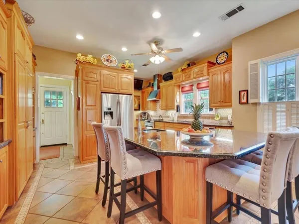 a kitchen with stainless steel appliances kitchen island granite countertop a refrigerator and a dining table