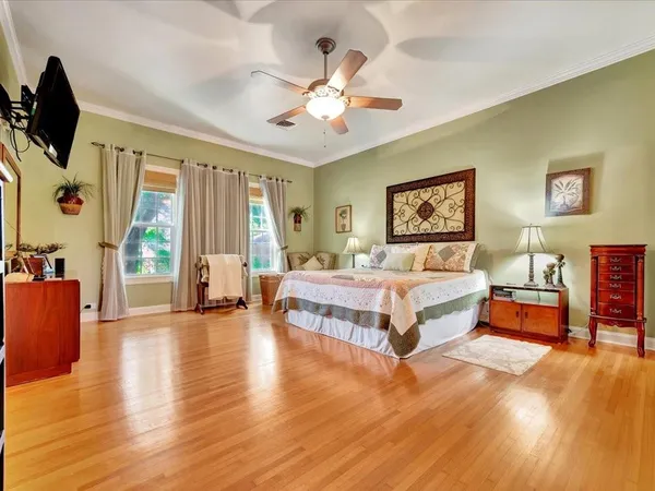 a spacious bedroom with a large bed a flat screen tv and windows
