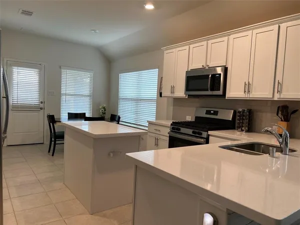 a kitchen with stainless steel appliances a stove a sink a microwave and a refrigerator