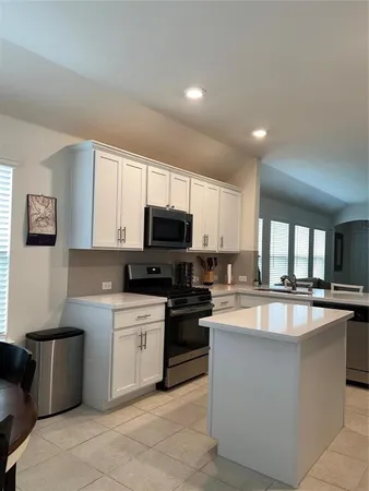 a kitchen with stainless steel appliances a white stove top oven a sink a window and white cabinets