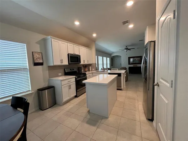 a large kitchen with a large counter top stainless steel appliances and cabinets