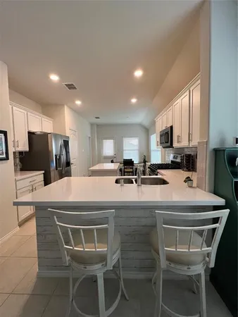 a kitchen with a dining table chairs refrigerator and microwave