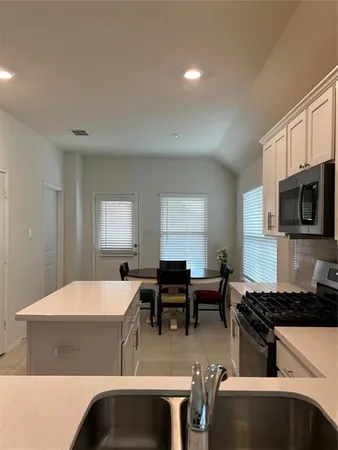 a living room with stainless steel appliances kitchen island granite countertop a stove and a sink