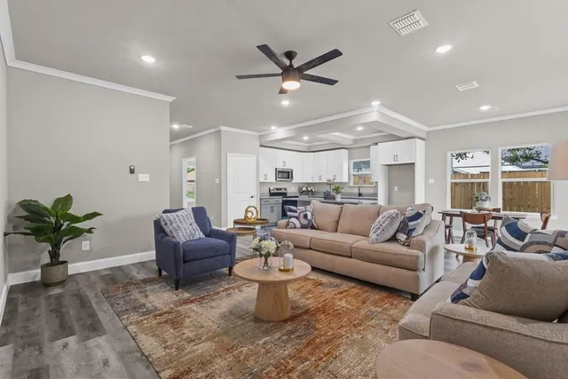 a living room with furniture a chandelier fan and a rug