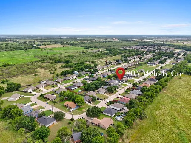 an aerial view of residential houses with outdoor space and trees