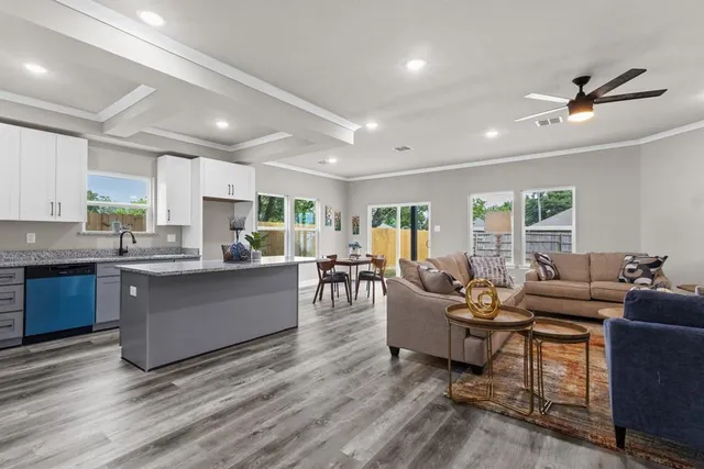 a living room with couches and kitchen view with wooden floor