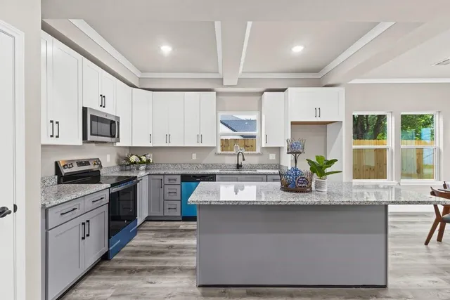 a large kitchen with granite countertop a stove top oven a sink a counter space and cabinets