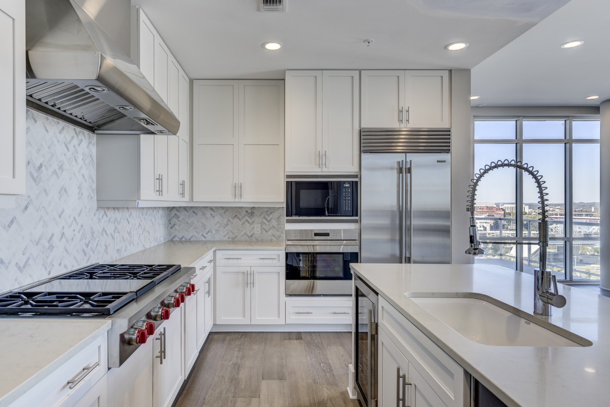 20 Rutledge Street, Unit 601 Nashville, TN 37210 - Photo 14 of 30 a kitchen with stainless steel appliances granite countertop a stove top oven a sink a refrigerator and white cabinets with wooden floor