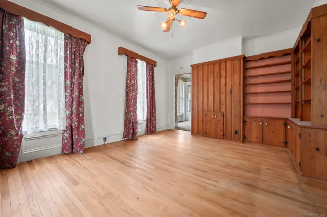 an empty room with wooden floor staircase and windows