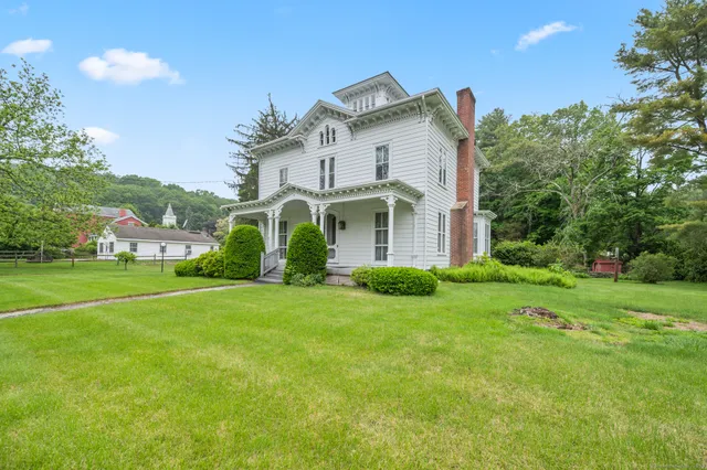 a view of a white house with a big yard and large trees