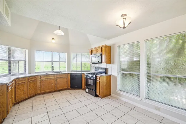 a large kitchen with a window and stainless steel appliances