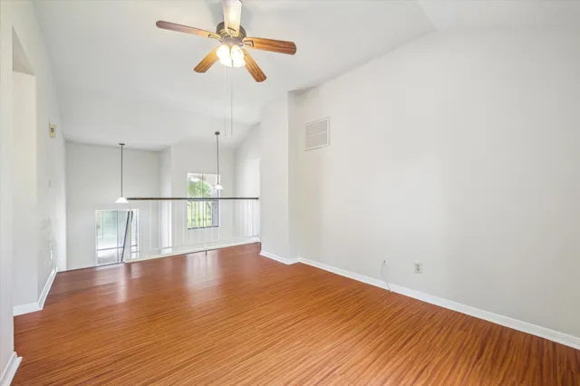 a view of a livingroom with wooden floor a ceiling fan and window