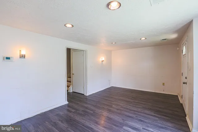 a view of an empty room with wooden floor and closet