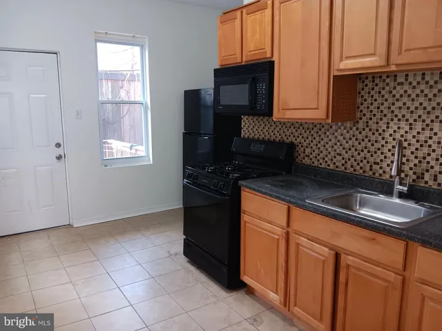a kitchen with granite countertop a sink a stove and a microwave