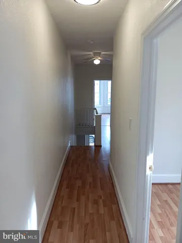 a view of a hallway with wooden floor and a bathroom